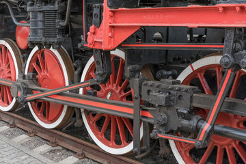 Red large iron wheels of an old vintage locomotive on railroad close-up. Wheels of a locomotive. Large wheels.
