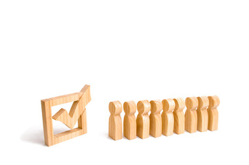 wooden human figures stand in a row next to wooden tick in the box. concept of elections and social technologies. Volunteers, parties, candidates, constituency electorates. Selective focus