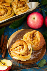 Naklejka na ściany i meble Fresh Homemade Rolls Buns with apples and cinnamon in glaze on a blue vintage wooden background.