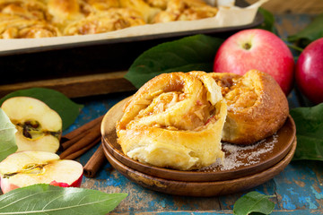 Fresh Homemade Rolls Buns with apples and cinnamon in glaze on a blue vintage wooden background.