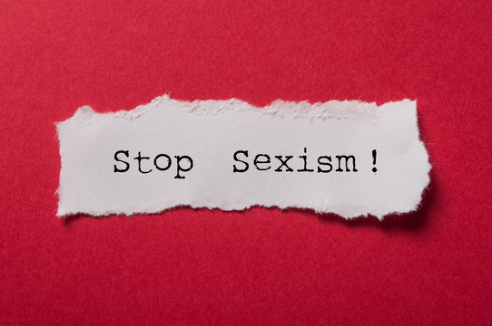 closeup of white torn paper on red paper background - Stop Sexism !