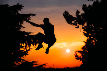 Man silhouette doing parkour jump activity on sunset