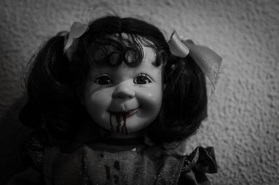 primer plano en blanco y negro de una mu&ntilde;eca con la cara malvada y sangre en la boca