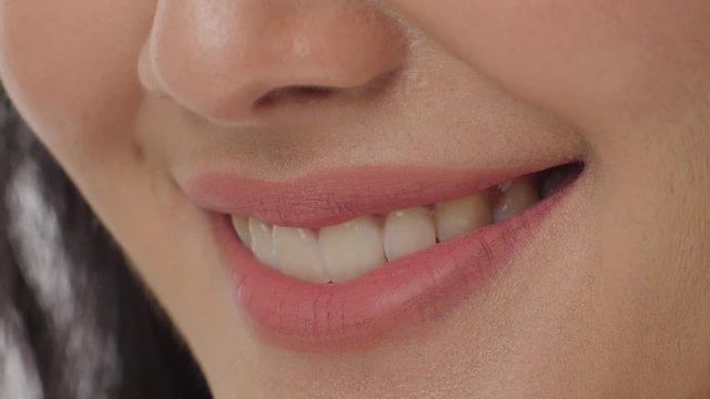 Close up of a woman smiling with teeth against a white background