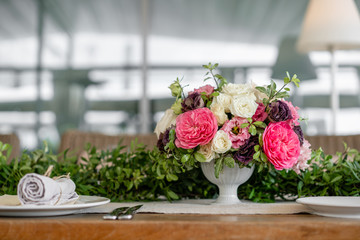 Neatly twisted into a tube dining room napkin decorated with a sprig of pistachio. Wedding Banquet or gala dinner. The chairs and table for guests, served with cutlery and crockery. party on terrace