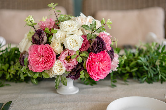 Arrangement of fresh flowers in pastel colors with a bright accent. Wedding background. table in a restaurant. different varieties of garden and shrub roses in a light vase on wooden table