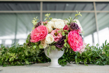Arrangement of fresh flowers in pastel colors with a bright accent. Wedding background. table in a restaurant. different varieties of garden and shrub roses in a light vase on wooden table