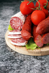 Food tray with delicious salami, pieces of sliced ham, sausage, tomatoes, salad and vegetable - Meat platter with selection - Cutting sausage and cured meat