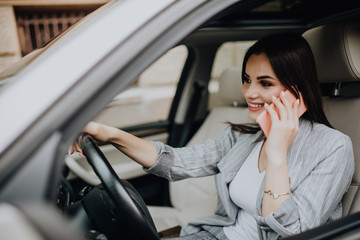 Portrait of woman driver talking her mobile phone while driving car.
