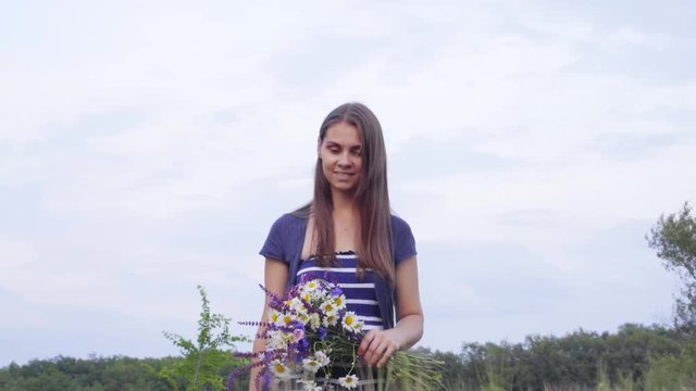young girl climbs the hill and collects a bouquet of wildflowers