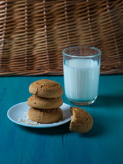 oatmeal cookies lie next to a glass of milk on a wooden background