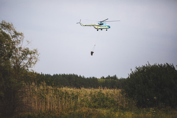 Fototapeta na wymiar Fire in forest. Helicopter dpirs and drops water in epicenter of incident