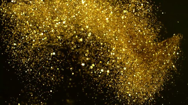 Super slow motion of glittering golden particles on black background. Shallow depth of focus. Filmed on high speed cinema camera, 1000 fps.