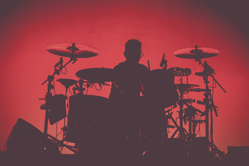 Silhouette of an unrecognizable man playing the drums	