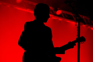 Silhouette of an unrecognizable man playing an electric guitar	