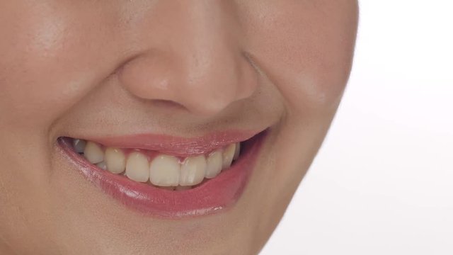 Close up of a woman smiling with teeth against a white background