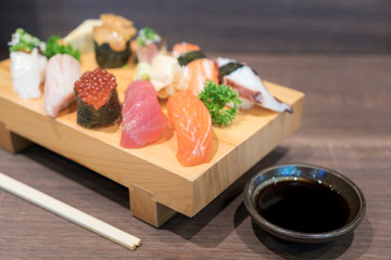 Close-up sushi and sashimi mixed on wooden plate on black wooden table. Japanese food.