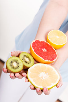 Woman holding fruits kiwi. orange, lemon and grapefruit