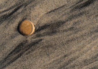 Fototapeta na wymiar Beautiful flat rock on sandy beach with water flow lines