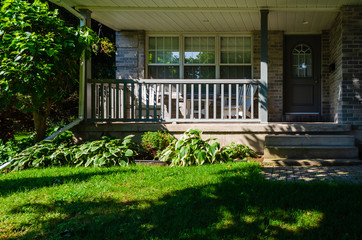 Shady covered front porch on a gray brick house