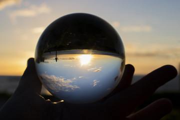 Fototapeta na wymiar Sunset on Beach Through Glass Ball