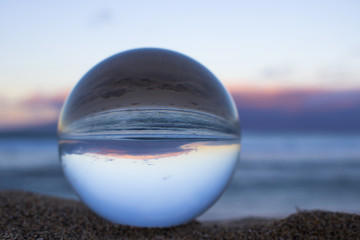 Fototapeta na wymiar Sunrise in Pink and Blue at Beach Through Glass Crystal Ball
