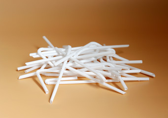 White disposable straws placed on a soft brown background.