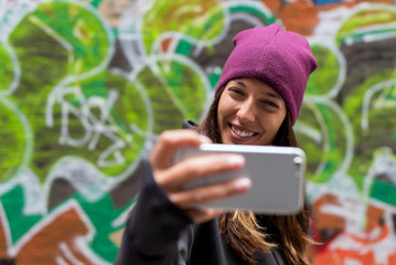 Young woman smiling and taking a selfie with her smartphone © Bisual Photo