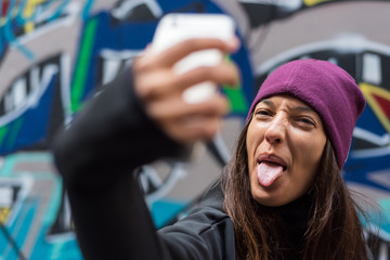 Young woman smiling and taking a selfie with her smartphone