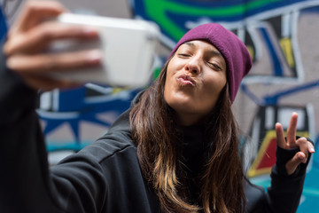 Young woman smiling and taking a selfie with her smartphone