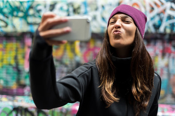 Young woman smiling and taking a selfie with her smartphone