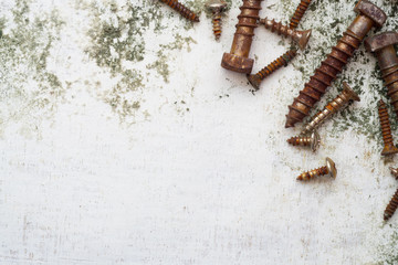 Rusty screws pattern. old steel bolts on grungy white wood background top view with copy space.