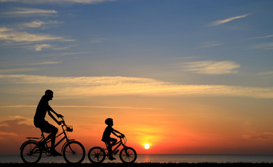 silhouette Father and son riding bicycle at sunset sky