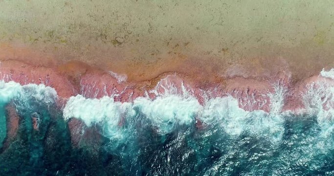 Waves crashing on a Tropical beach in French Polynesia. Half with the blue waves and half with a beach and coral reef in the Pacific Ocean - aerial view with a drone - Travel tropical concept