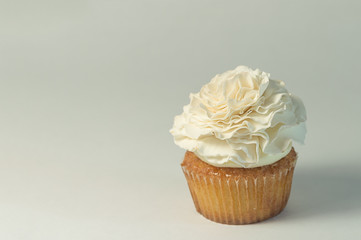 Single cupcake with edible sugar flower topper. White background with copy space