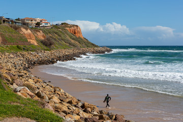 A surfer running along the sand in to the water at Christies Beach South Australia on 6th September 2018
