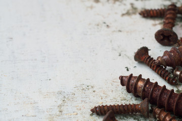Close up selective focus of rusty screws. old steel bolts on grungy white wood background