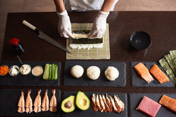 Close-up viev of chef hands preparing japanese food. Chef making sushi rolls at restaurant with...