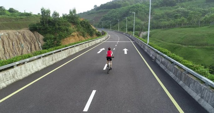 Aerial view of woman cyclist riding bike  on highway road 