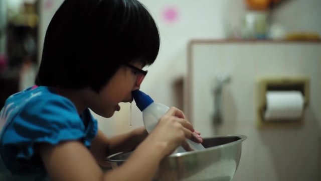 Portrait of Asian girl cleaning her nose by squeezing the medical plastic bottle to inject the saline into nasal