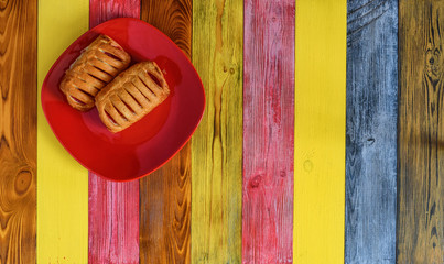 puff pastry with jam on a red plate on a multicolored wooden background