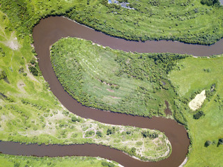 Aerial landscape of winding river in green field. Aerial shoot of beautiful nature texture from drone