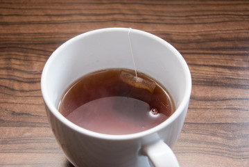 Black tea in a white cup on a wooden surface.