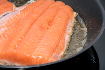 The fillet of salmon is fried in a frying pan.