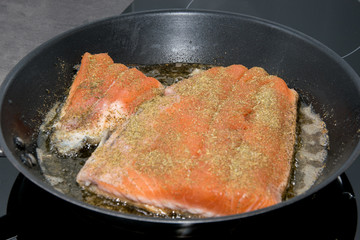 The fillet of salmon is fried in a frying pan.
