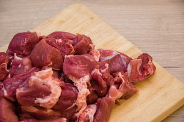 Pieces of sliced raw meat on a wooden board.