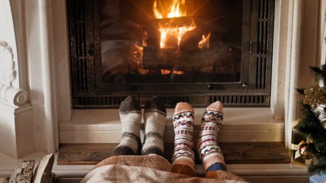 4k footage of romantic couple in socks warming at burning fireplace