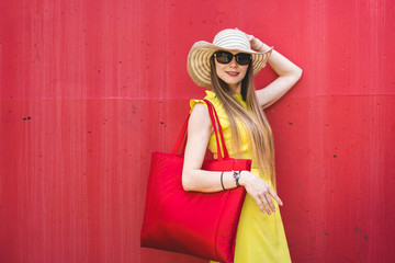 Beautiful smiling woman in a yellow dress in front of a red wall