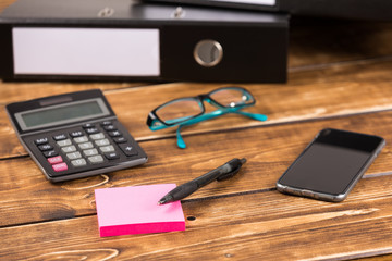 desk with folder, smartphone, glasses and calculator