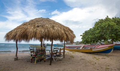 Obraz na płótnie Canvas Typical Jamaican beach shelter and fishing boats